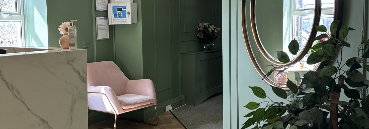 Office reception with green walls, pink armchair and white marble reception desk