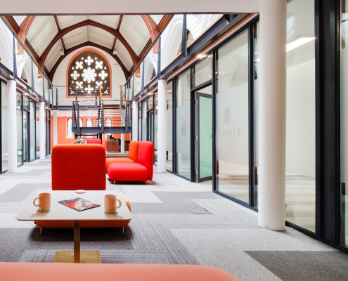 Office space in modernised church. Red seating and grey carpet with white architecture